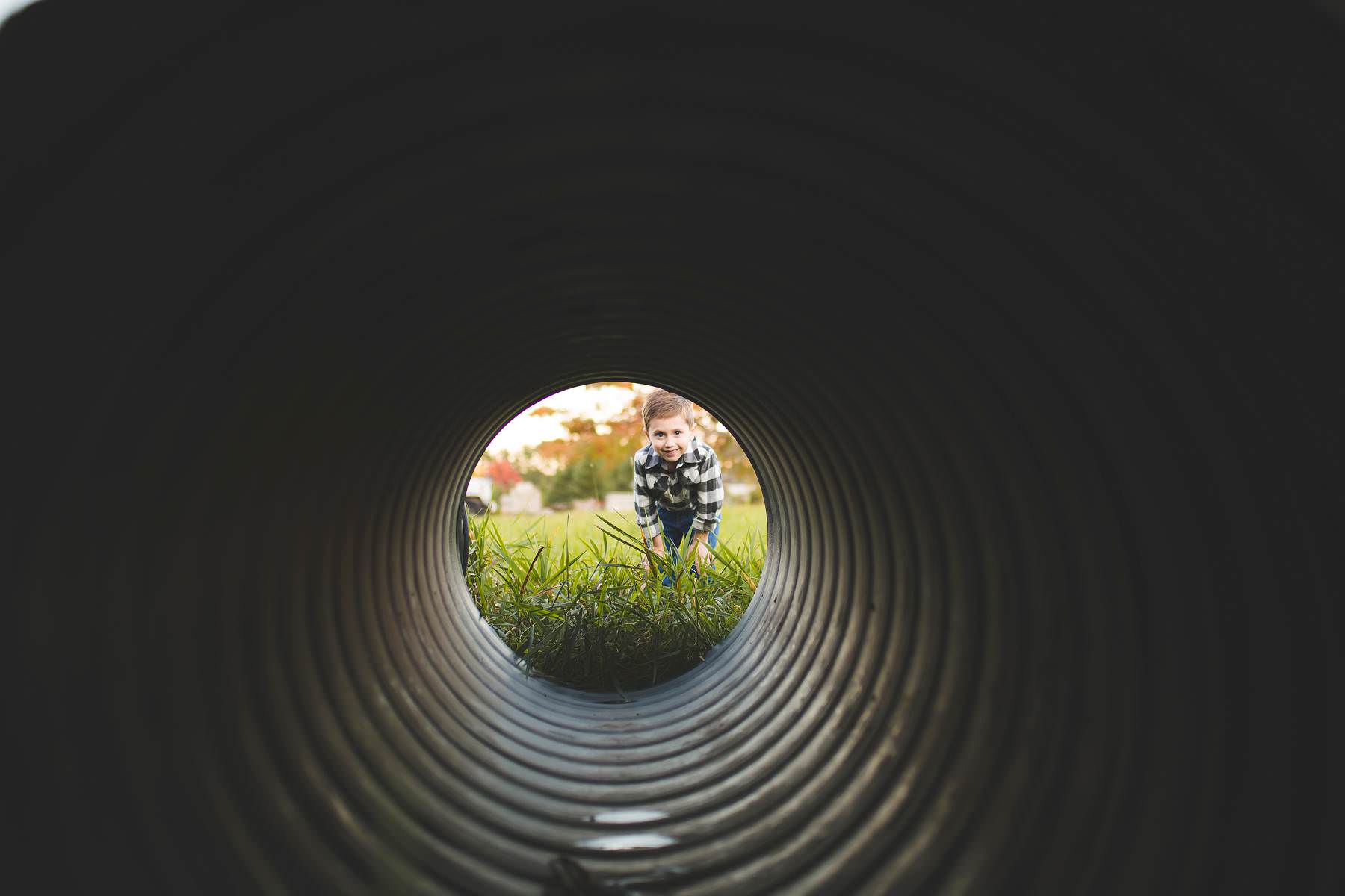 boy plays hide and seek on tree farm