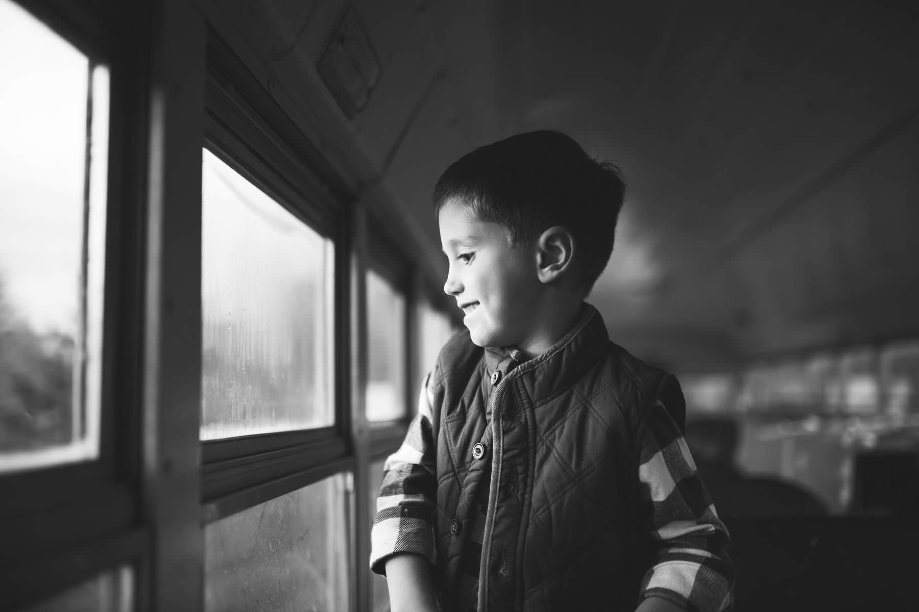 boy looks out window of antique school bus