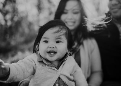 toddler watches big sister run in moms arms