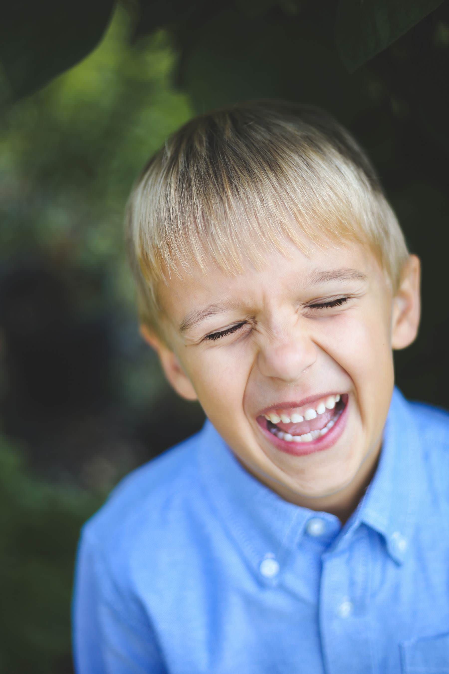 little boy in blue laughs and shows his missing tooth