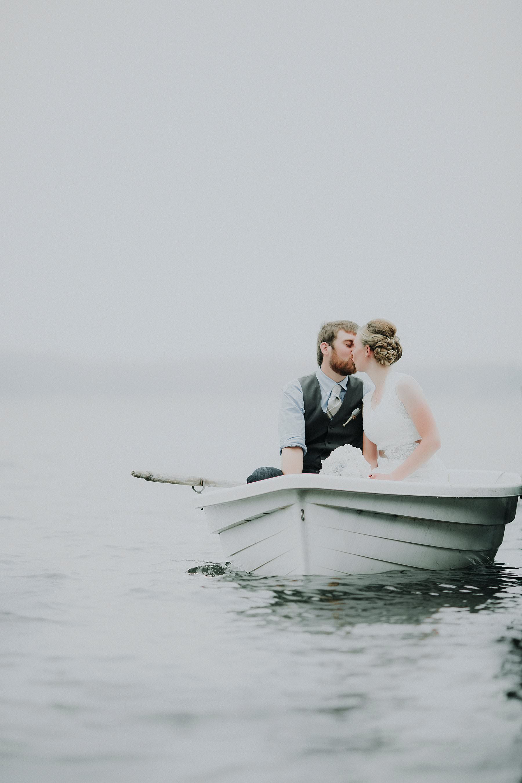 bride and groom in row boat kissing minnesota