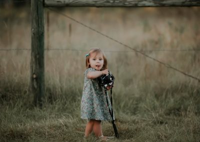 little girl in blue dress holding vintage camera